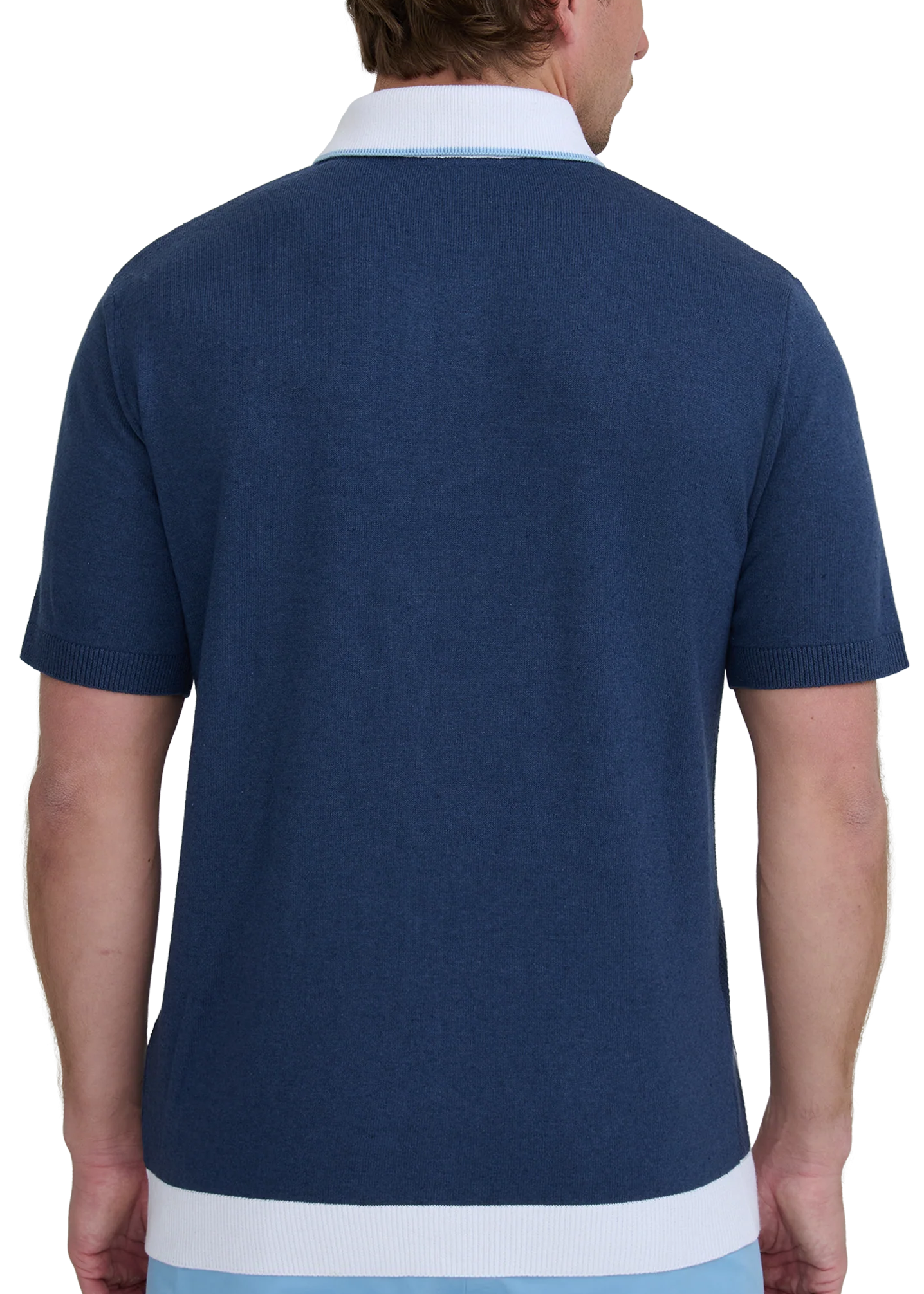 Man wearing a navy polo shirt with a white collar and light blue pants on a white background